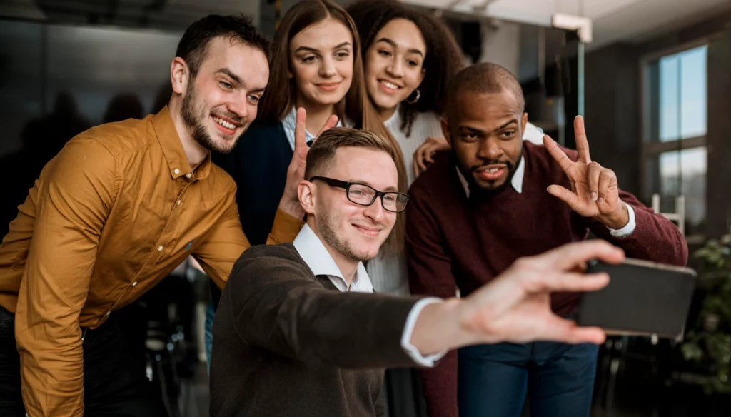 smiley colleagues taking selfie meeting scaled